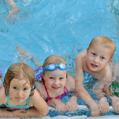 Lapsia uima-altaan reunalla uimakoulussa.