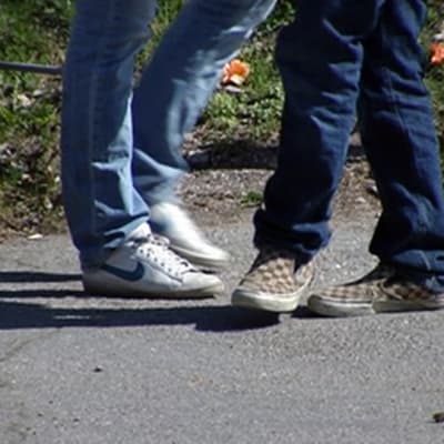 Kaksi anonyymia nuorta seisoo asfaltilla.