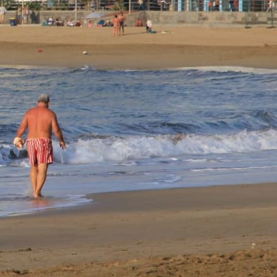 Kuvassa mies kävelee vesirajassa hiekkarannalla Gran Kanarialla Las Palmasissa. 