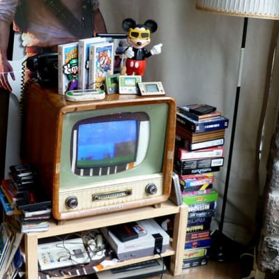 Vanhaan televisioon upotettu pelikonsoli ja vanhoja pelikasetteja.