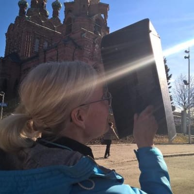 Nainen katsoo auringonpimennystä hitsauslaisen läpi Tampereella