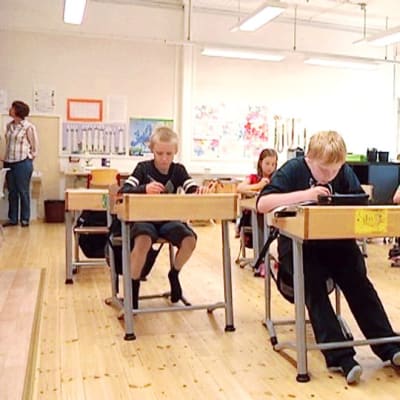 Alakoulun lapset istuvat pulpeteissa. 