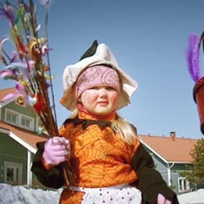 Pääsiäisnoidaksi pukeutunut lapsi kantaa virpomisvitsoja.