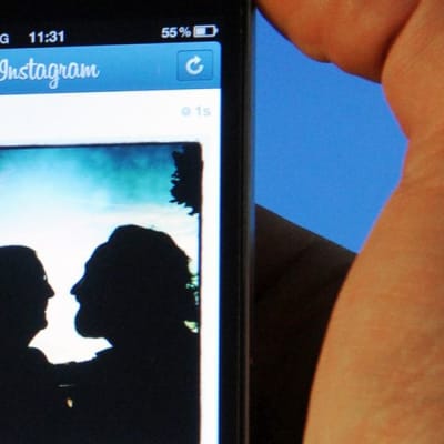 Mies katsoo älypuhelimeltaan kuvaa Instagram-kuvanjakopalvelussa.