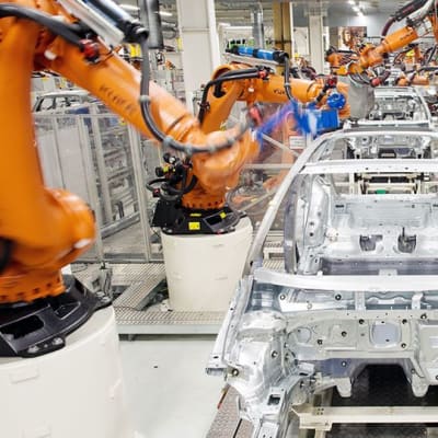 Robotit kasaavat autoja Volkswagenin tehtaan liukuhihnalla Saksan Wolfsburgissa.