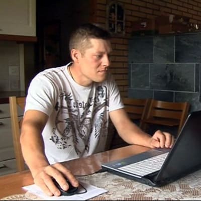 Mies käyttää kannettavaa tietokonetta.