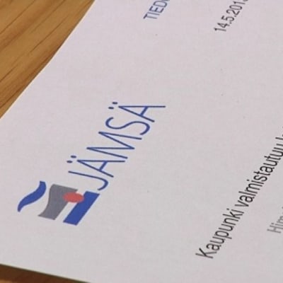 Pöydällä on paperi, jonka otsikossa kerrotaan Jämsän valmistautuvan kylpylähotellihankkeeseen.