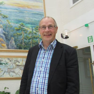 Ylitornion kunnanjohtaja Tapani Melaluoto kunnantalolla Aavasaksan maisemaa esittävän maalauksen edessä.