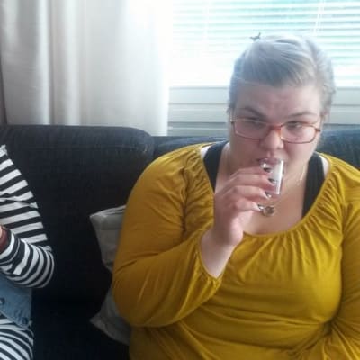 Milla Häkkinen ja Sofia Saarinen istuvat sohvalla ja maistelevat terveysjuomaa.