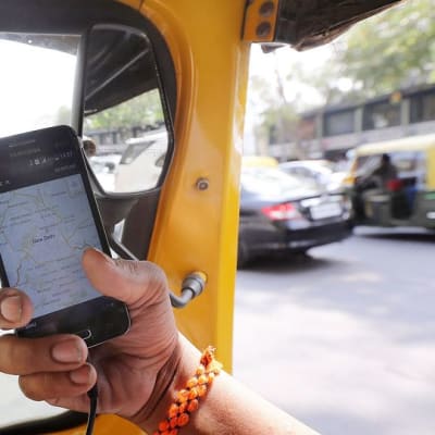 Intialainen tutkii uber-sovellusta autossaan Delhissä.