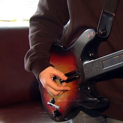 Poika soittaa Guitar Hero -tyyppisiä pelejä varten tarkoitetulla kitaralla.