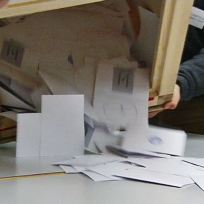 Virkailijat kaatavat äänestyslipukkeita vaaliuurnasta pöydälle.