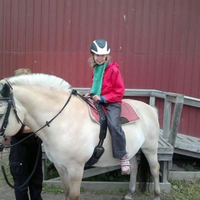 Tyttö hevosen selässä.
