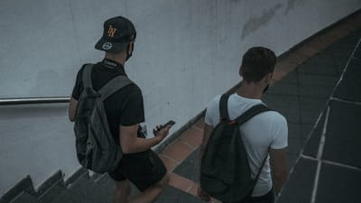 Två unga män går ner för trappor till en metrostation. De är fotograferade bakifrån.