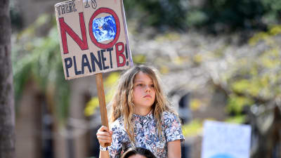 Liten flicka på en mans axlar håller i en skylt med texten "There is NO planet B".