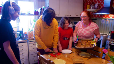 En mor och tre barn lagar mat tillsammans.