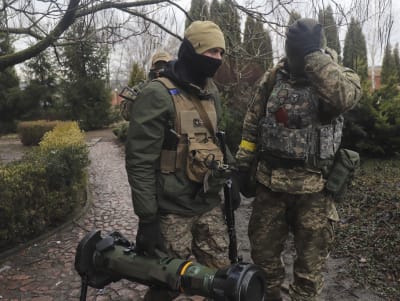 Tre ukrainska soldater i full utrustning med vapen talar med varandra.