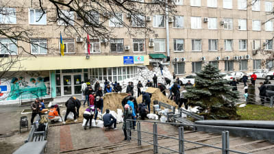 Frivilliga lastar sandsäckar framför ett sjukhus i Zaporizjzja för att skydda det mot angrepp.
