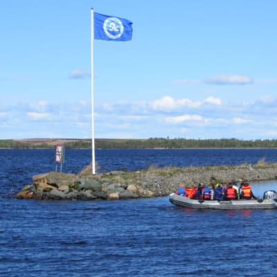 Kumivene Kemin Uleninrannan satamassa, sininen Roope-lippu liehuu salossa.