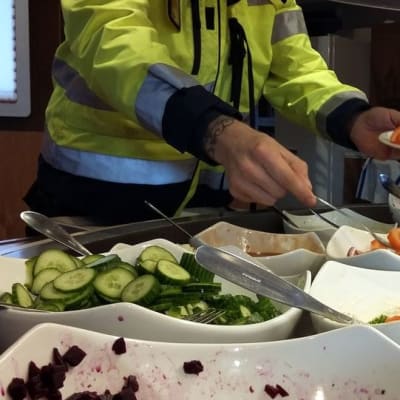 Mies ottaa salaattia lautaselle