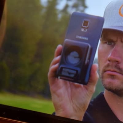 Mies käyttää kännykällään Caddieye-väylämittaria mainosvideolla