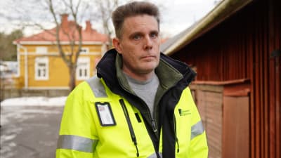 Man står framför rött och fult trähus.