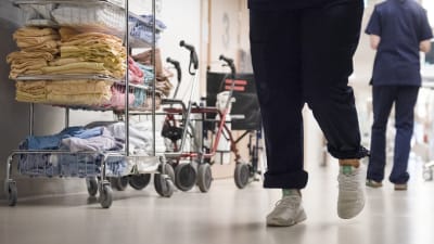 Sjukskötare går i en sjukhuskorridor. Man ser bara fötter och ben.
