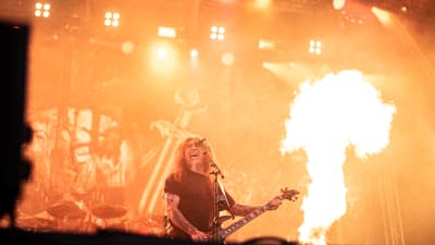 Tom Araya på scenen med Slayer. I bakgrunden är det stora eldsflammor från pyrotekniken.