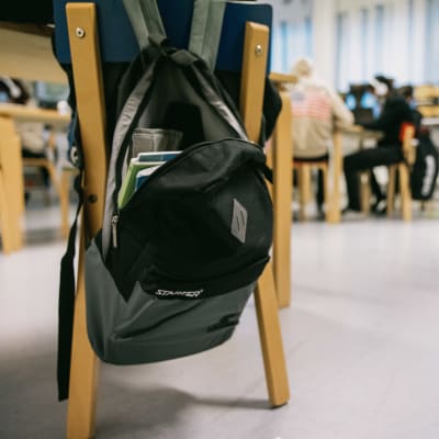 Reppuja roikkuu tuoleilla koululuokassa.