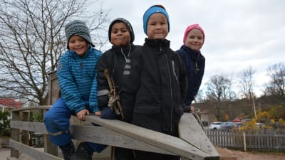 Fyra barn i en klätterställning som ser ut som en båt på en daghemsgård. 