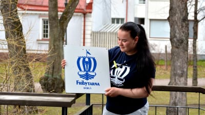 Scoutledare står ute med skylt.