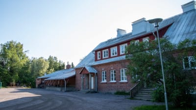 Ett avlångt, stort tegelhus vid en sandplan.