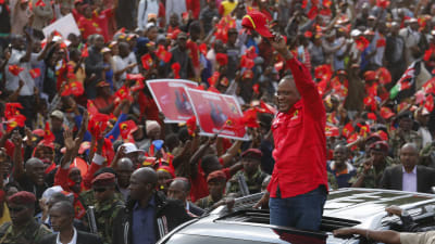 Kenyas president Uhuru Kenyatta vinkar till sina anhängare från en limousine.