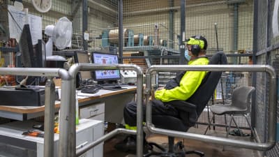 En pappersarbetare övervakar paketeringen av pappersrullar på UPM:s fabrik i Jämsä.