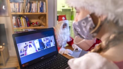 Tonttutyttö katsoo tietokoneelta etäyhteydellä joulupukkia.