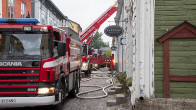 Brandbilar står parkerade på grund av en brand i ett trähuskvarter.
