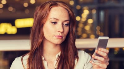 Kvinna tittar fundersamt på sin smarttelefon