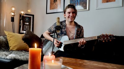 Musikern André Linman spelar gitarr och sjunger framför videokamera.