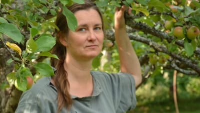 Tuija Kuoppamäki står under ett äppelträd.