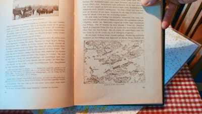 Henrik sundbäck visar en bok med en karta över hur trupperna stod.