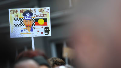 Demonstranter i Sydney, Australien håller i en skylt med texten "Stoppa ursprungsfolkens död i polishäkten" . Demonstranterna protesterar mot att så många aboriginer dött i polishäkte i Australien.