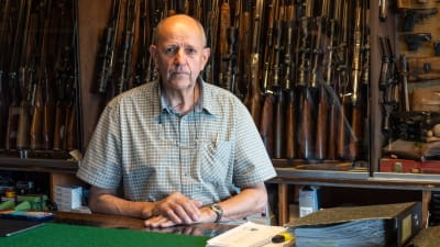 Porträtt på vapenhandlaren William Wadstein. Han står framför flera vapen i sin affär.