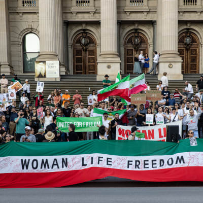 En grupp demonstranter med en flagga där det står "WOMAN LIFE FREEDOM"
