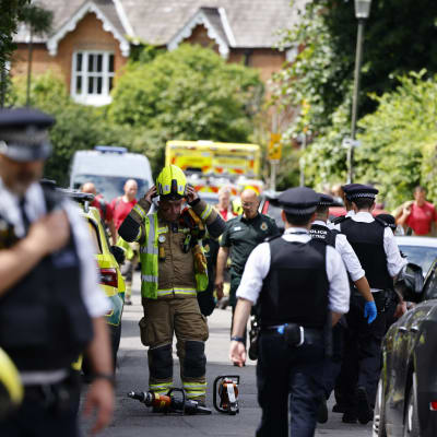 Ett stort antal poliser och utryckningsfordon på en smal gata i södra London. En brandman tar av sig hjälmen medan poliser går förbi.