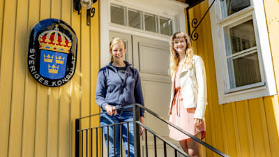 Laura Langh-Lagerlöf och Julia Granholm står framför Sveriges vapensköld