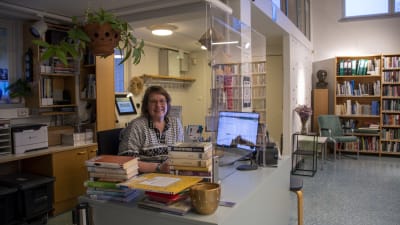 En kvinna sitter vid en desk i ett bibliotek.