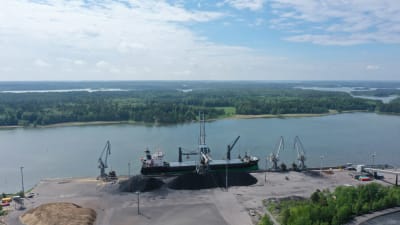 Flygbild på en hamn, ett lastfartyg och kranar.