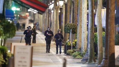 Poliser vandrar längs i övrigt folktomma Champs-Elysees i Paris, i kölvattnet efter en attack där en polis misste livet.