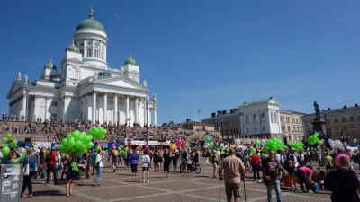 Senatstorget fylls med pridedeltagare och gröna ballonger under Helsingfors prideparad 2016.
