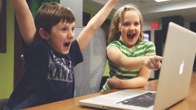 två blada barn sitter vid en dator i skolan